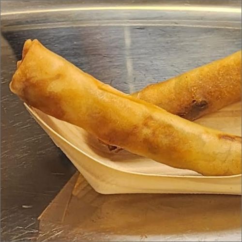 Two egg rolls are sitting on a wooden tray on a table.