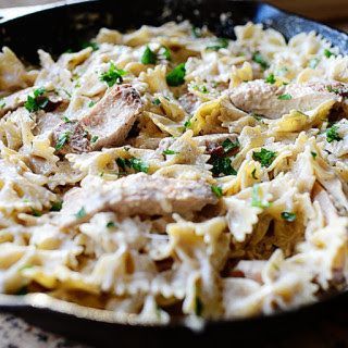 A skillet filled with pasta and chicken in a creamy sauce.