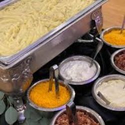 A buffet table topped with bowls of food and a tray of mashed potatoes.