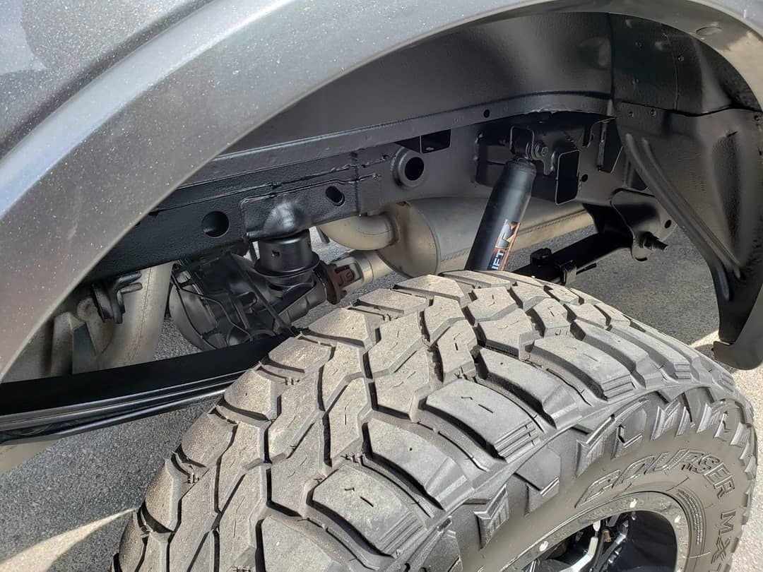 A close up of a truck 's fender and tire.