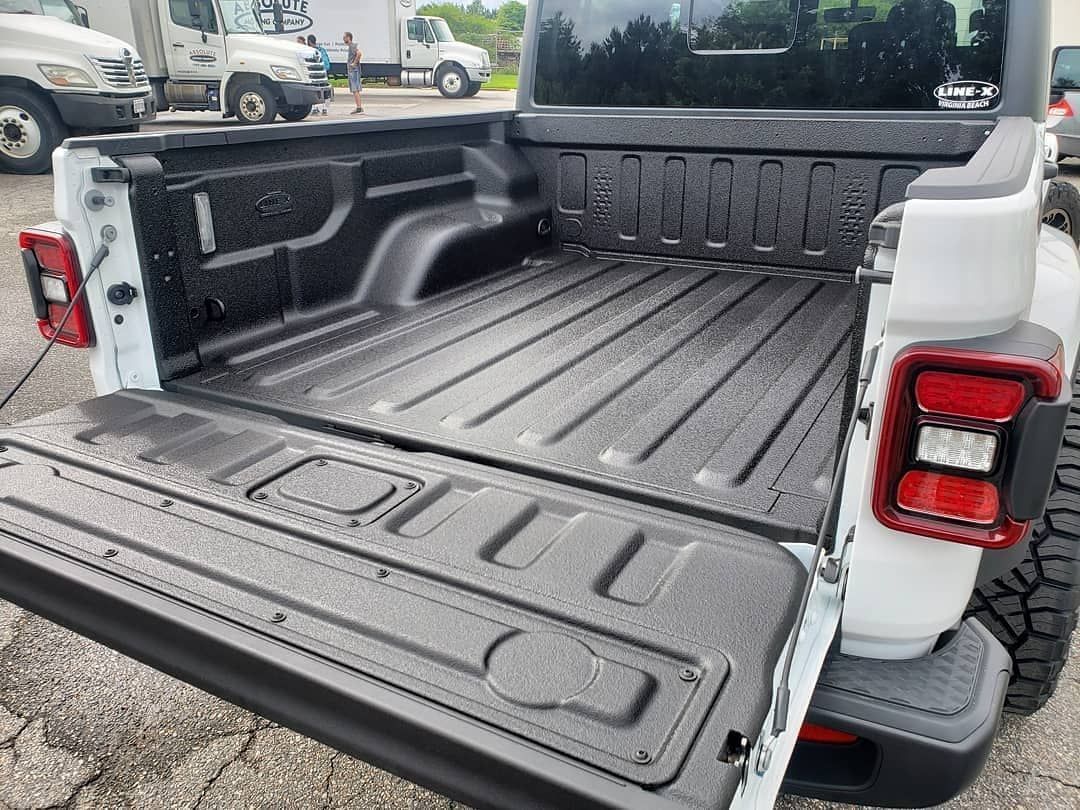 The back of a white jeep wrangler with the bed open.