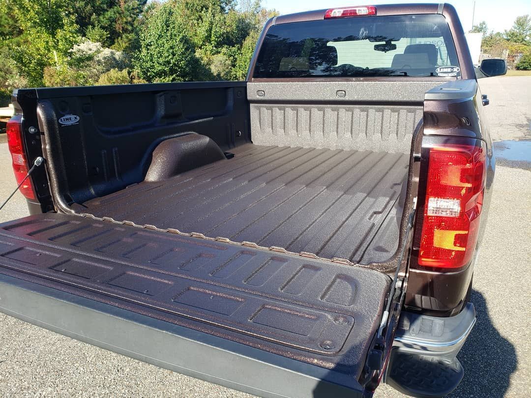 A truck with its bed open is parked in a parking lot.