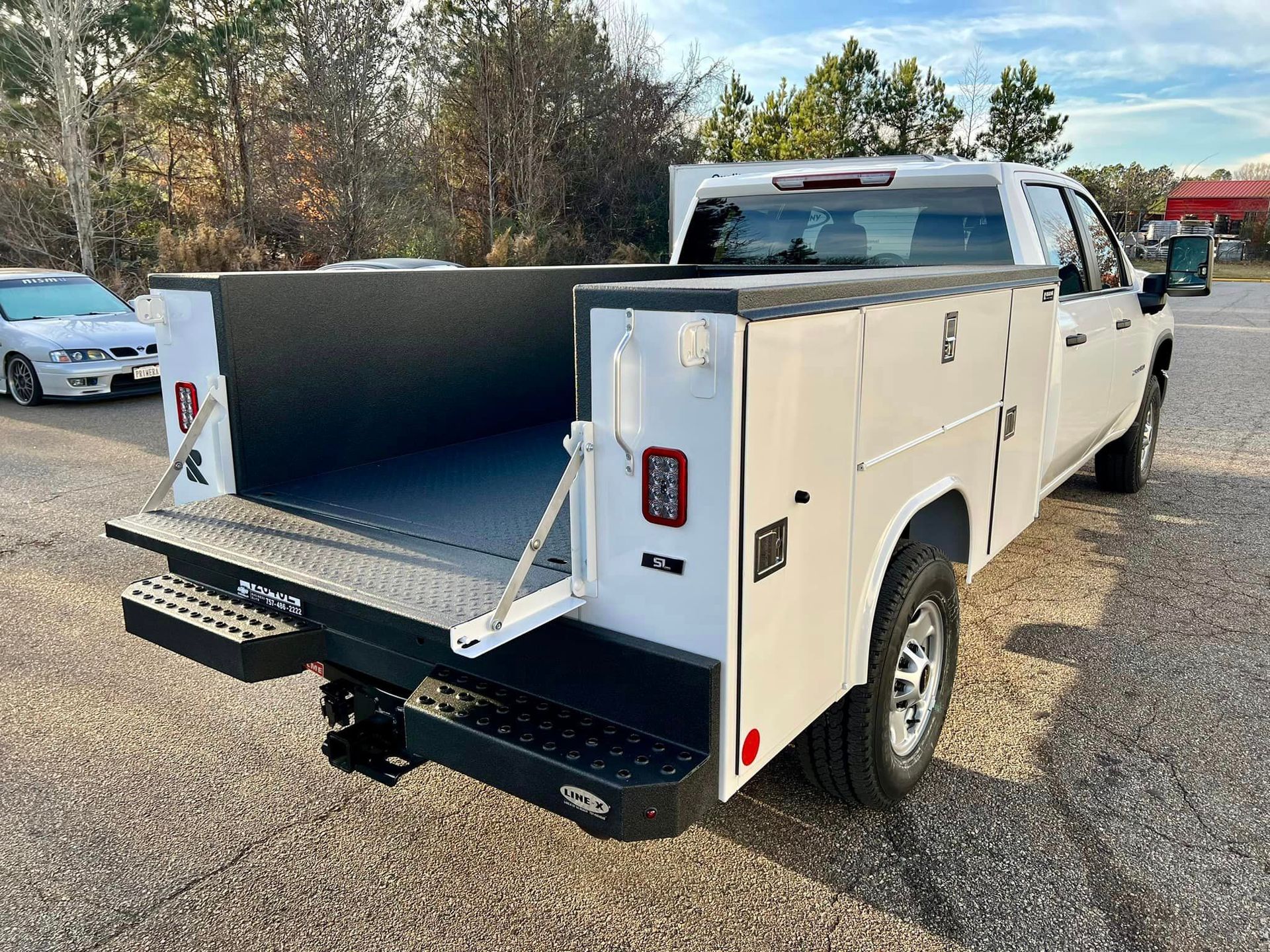 A white truck with a utility bed is parked in a parking lot.