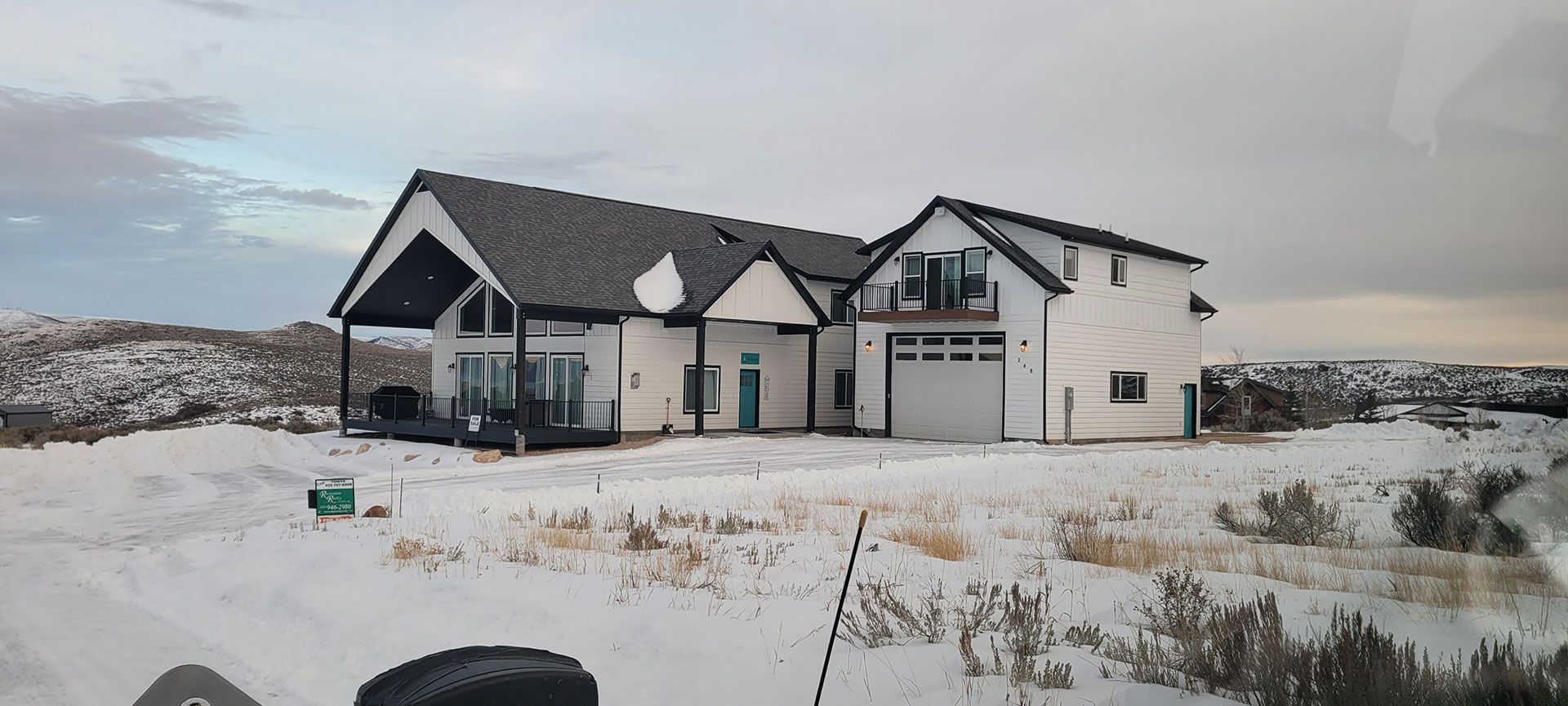 White house with black roof in snowy landscape.
