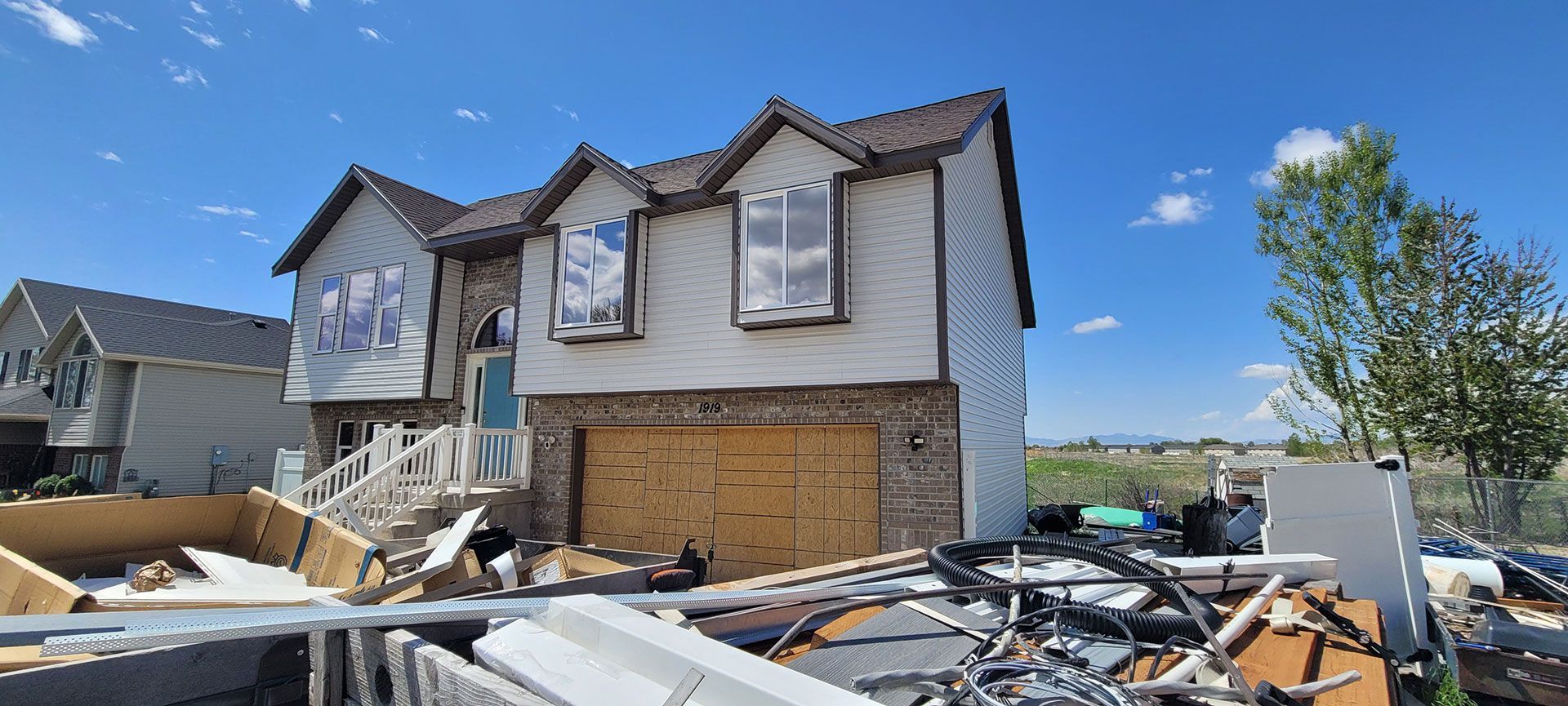 A two-story house under construction with exposed wood and a messy construction site. Clear blue sky.