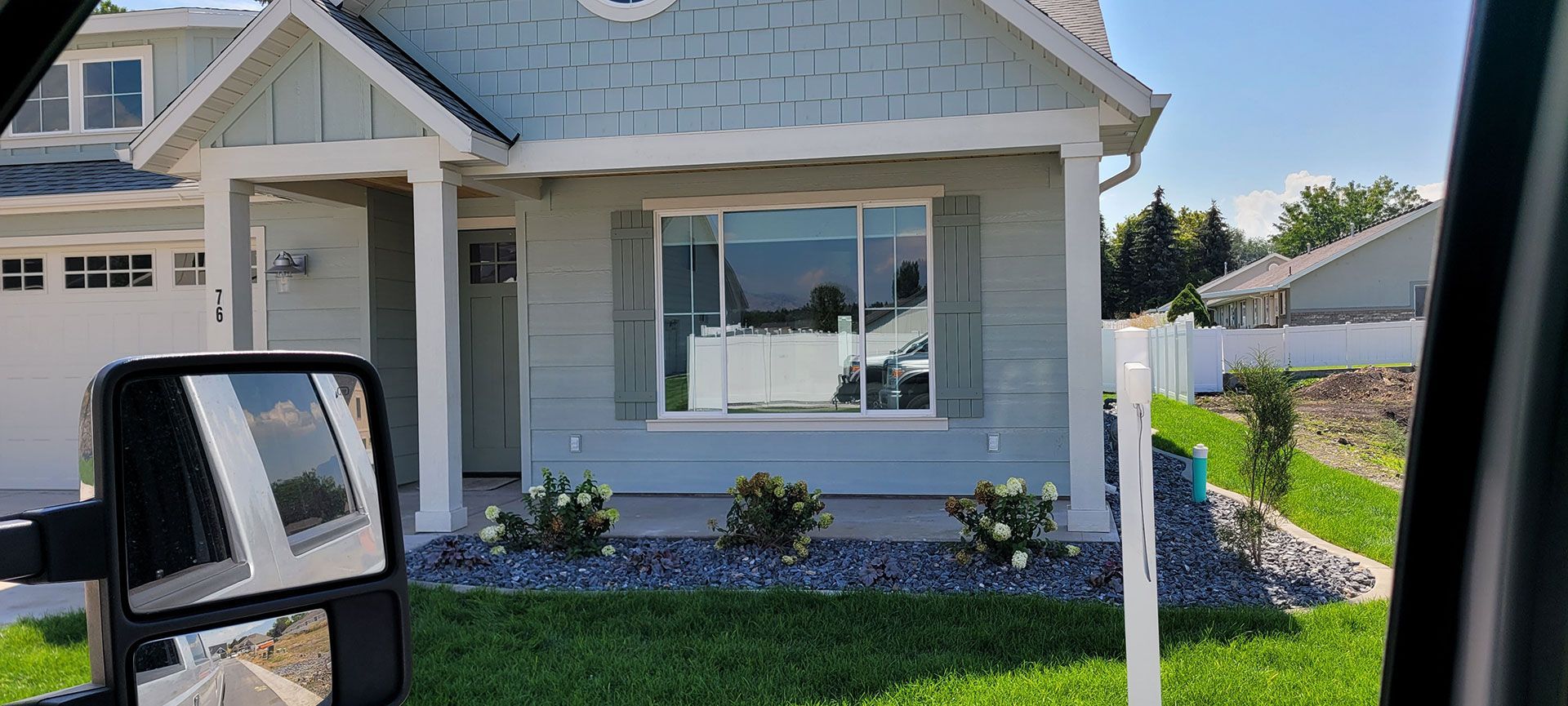 Blue house with white trim, green shutters, and a lawn.