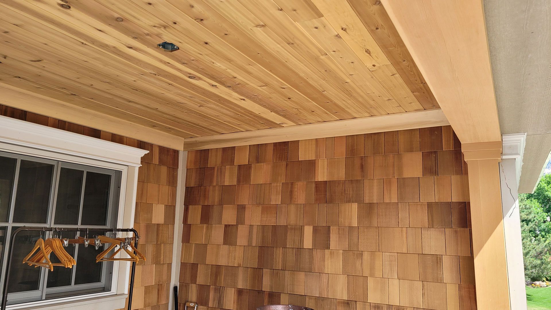 Wooden porch with cedar shake walls and ceiling.