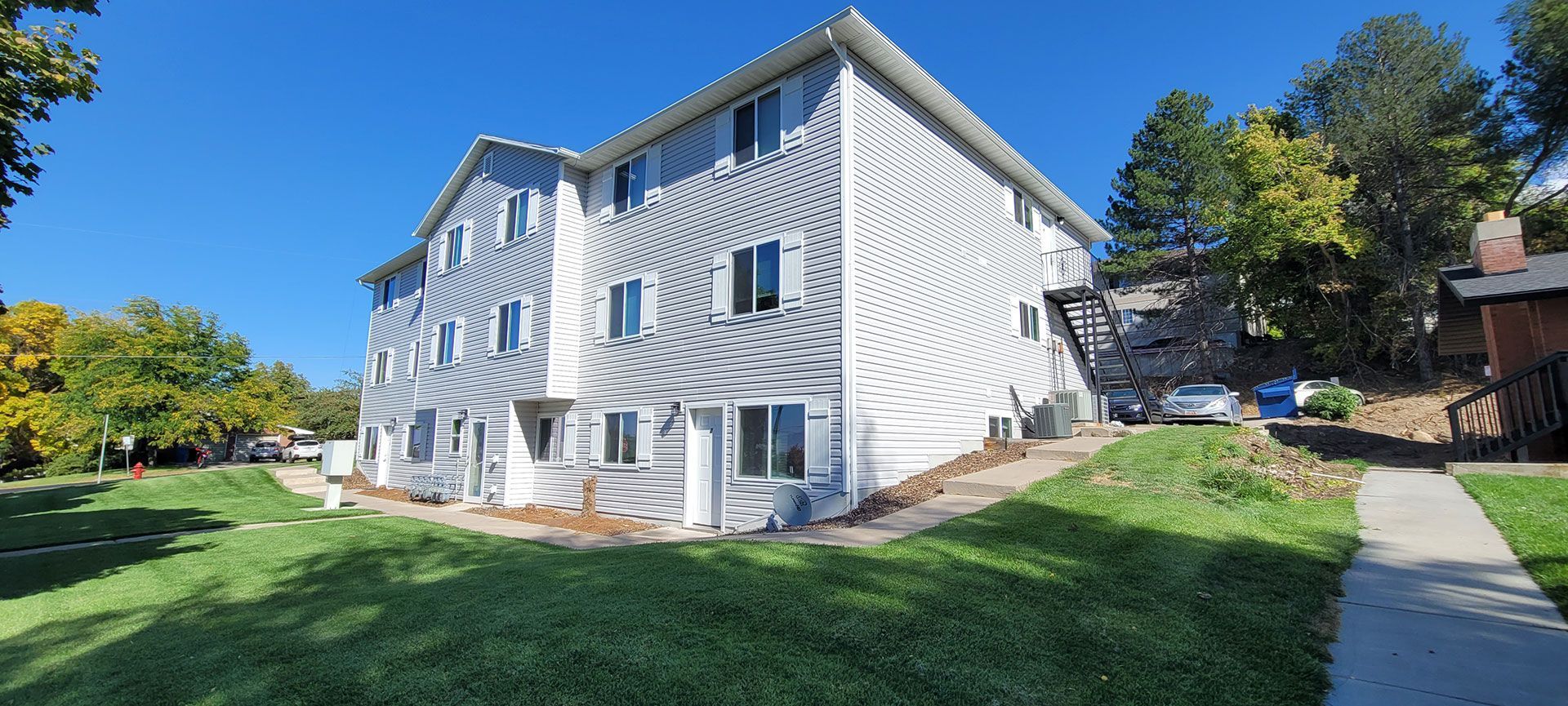 A three-story building covered in white, swirly fabric on a sunny day. Green grass and trees surround it.