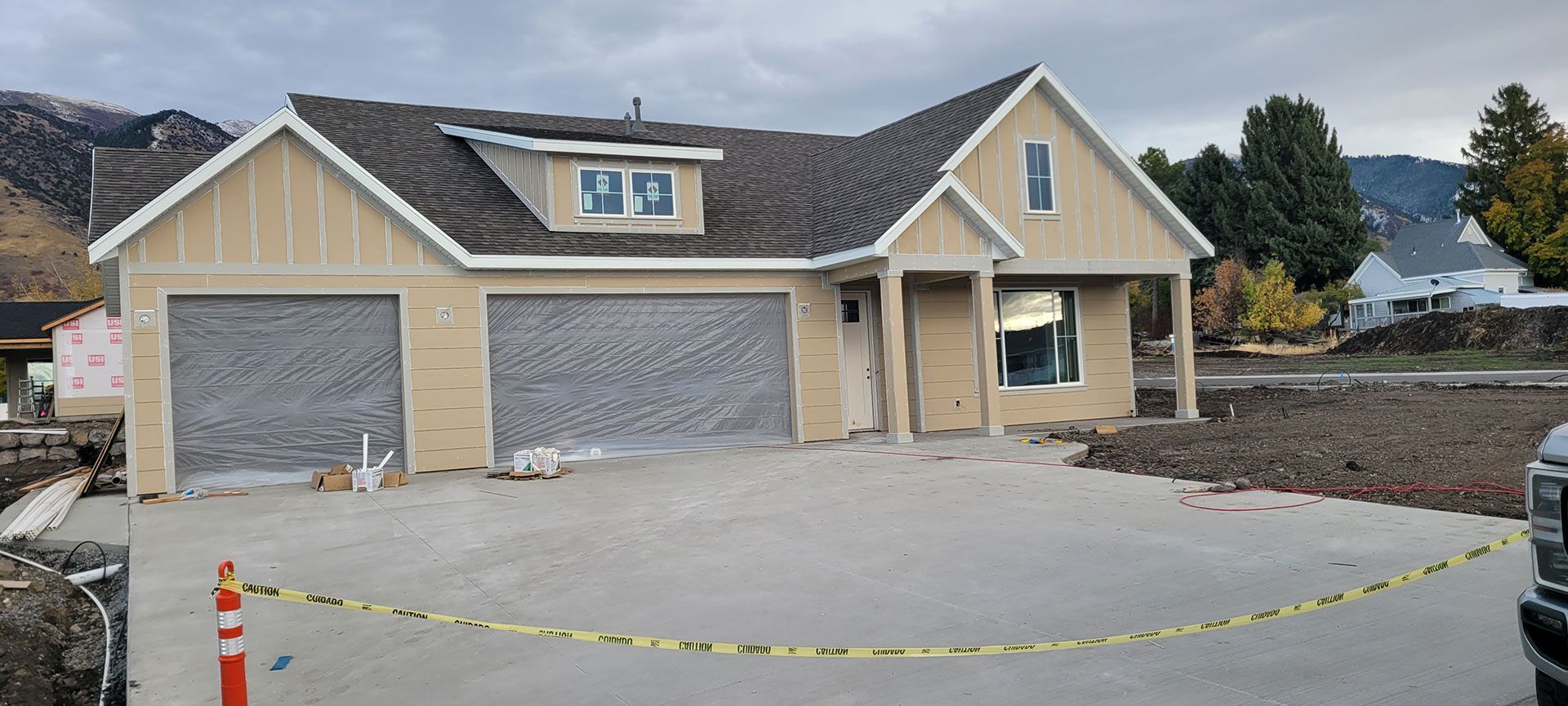 New house under construction. Light beige siding with gray garage doors and concrete driveway.