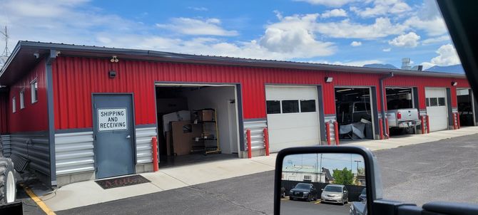 A red auto repair shop with multiple garage bays, a blue door, and vehicles inside.