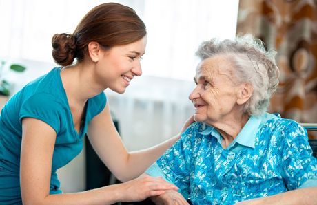 A young woman is talking to an older woman in a wheelchair.