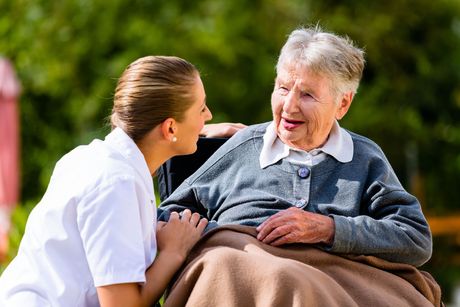 A nurse is talking to an elderly woman in a wheelchair.