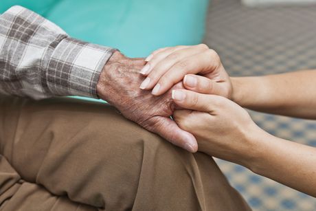 A woman is holding the hand of an older man.