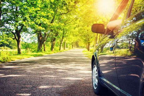 A car is parked on the side of a road surrounded by trees.