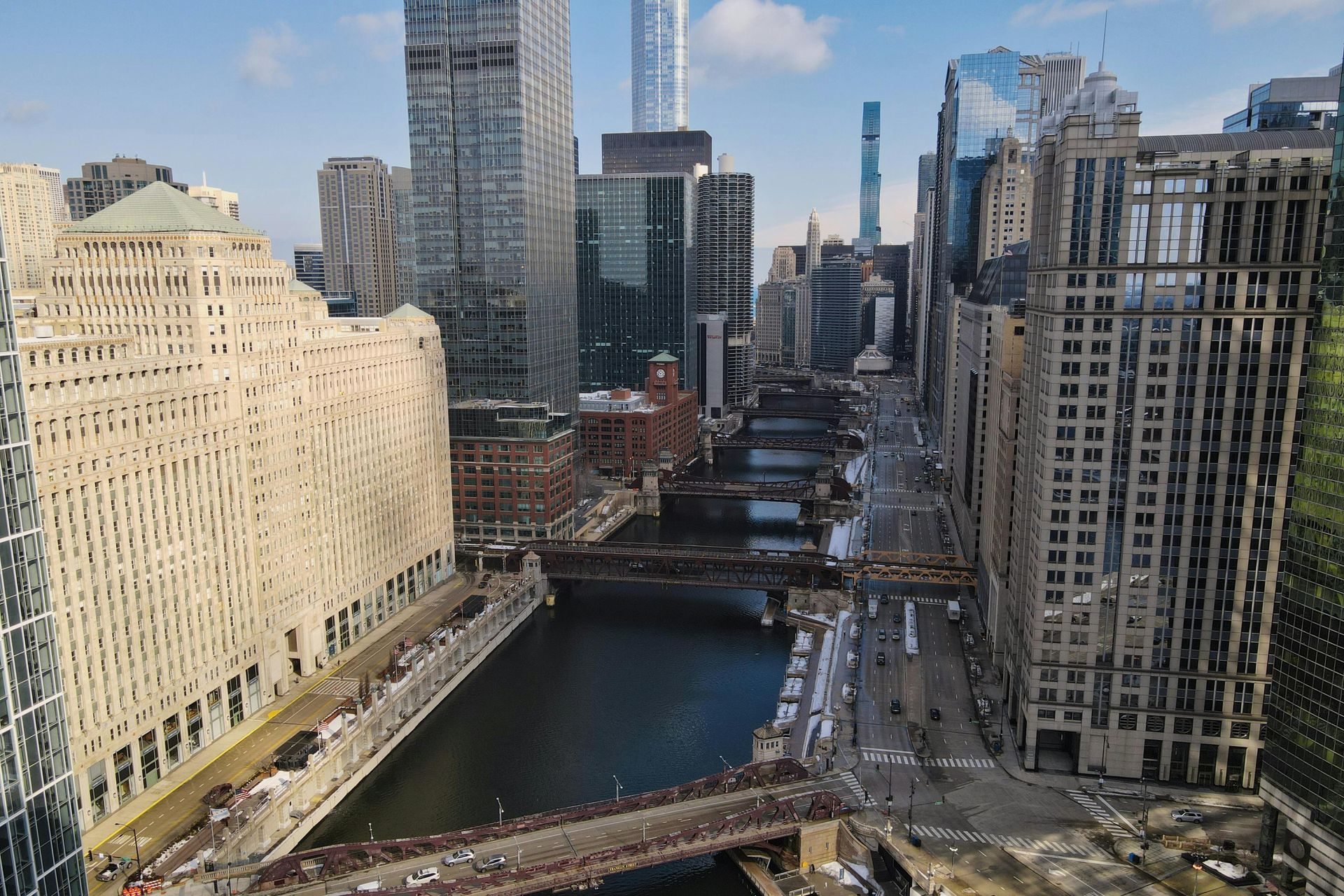 Chicago River flowing through downtown skyscrapers, bridges, and sunny skies.