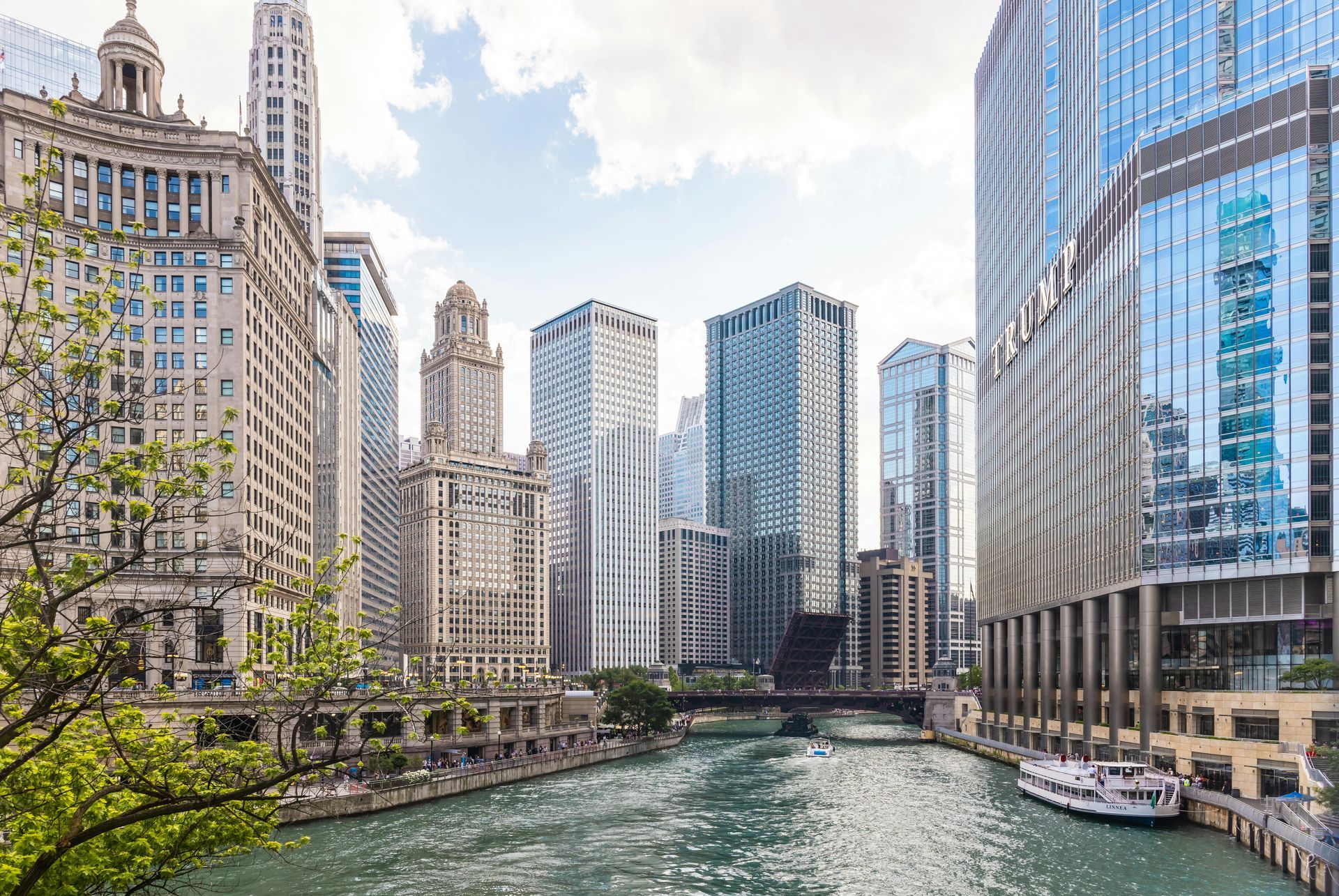 Chicago River with skyscrapers and a bridge, sunny day.