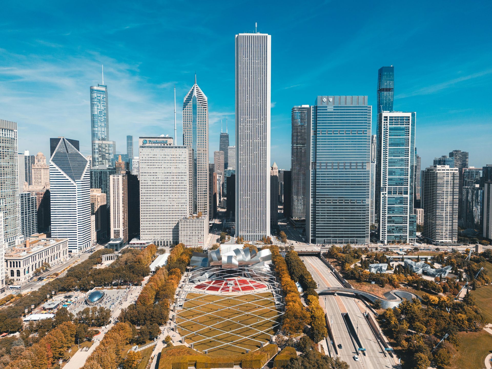 Chicago skyline with skyscrapers, park, and highway under a clear, blue sky.