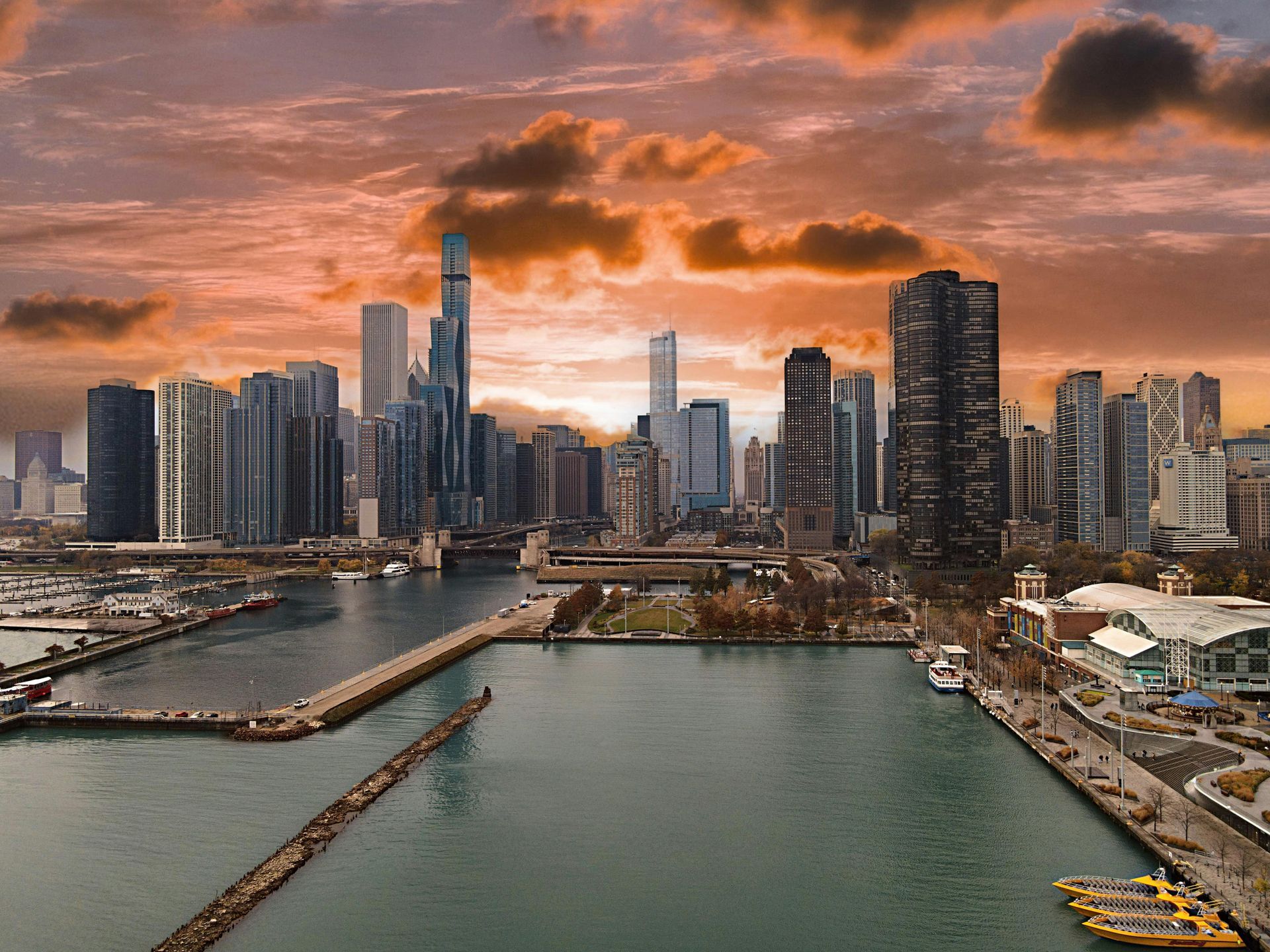 Chicago skyline at sunset. Skyscrapers frame a harbor under an orange and gray sky.