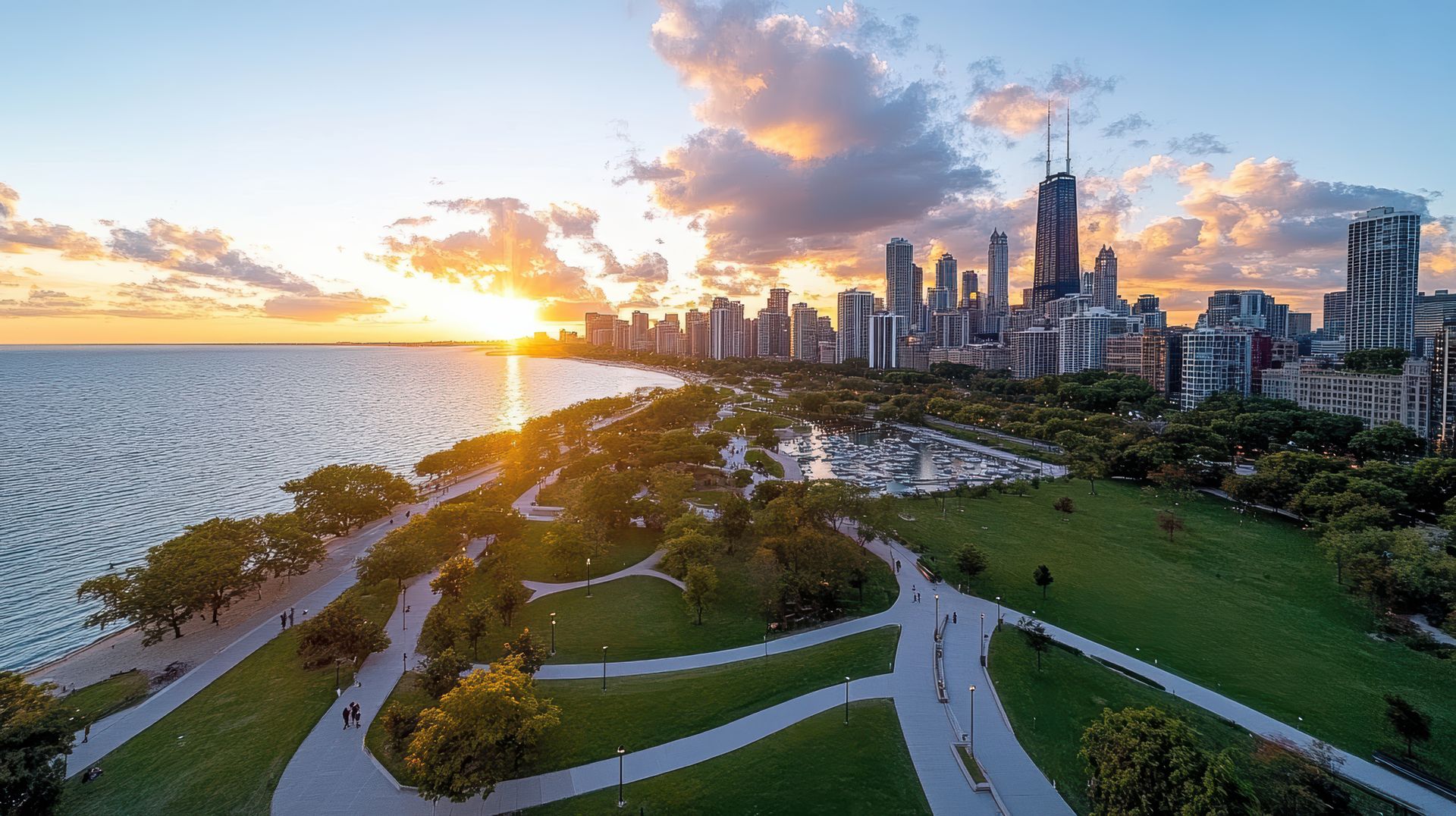 Chicago skyline at sunset, view from park by Lake Michigan. Buildings silhouetted, golden light.