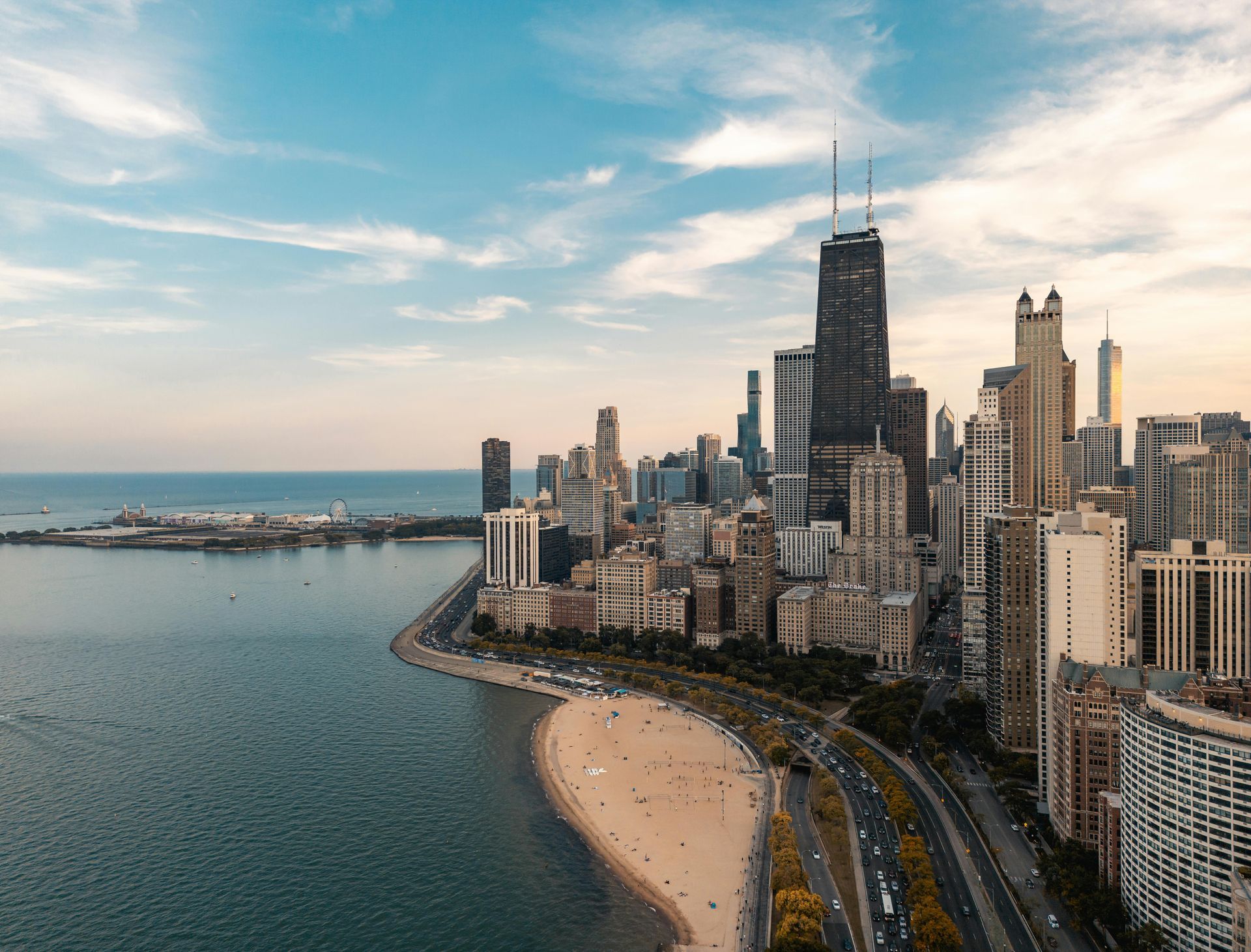 Chicago skyline along Lake Michigan with a sandy beach, shoreline road, and tall skyscrapers at dusk