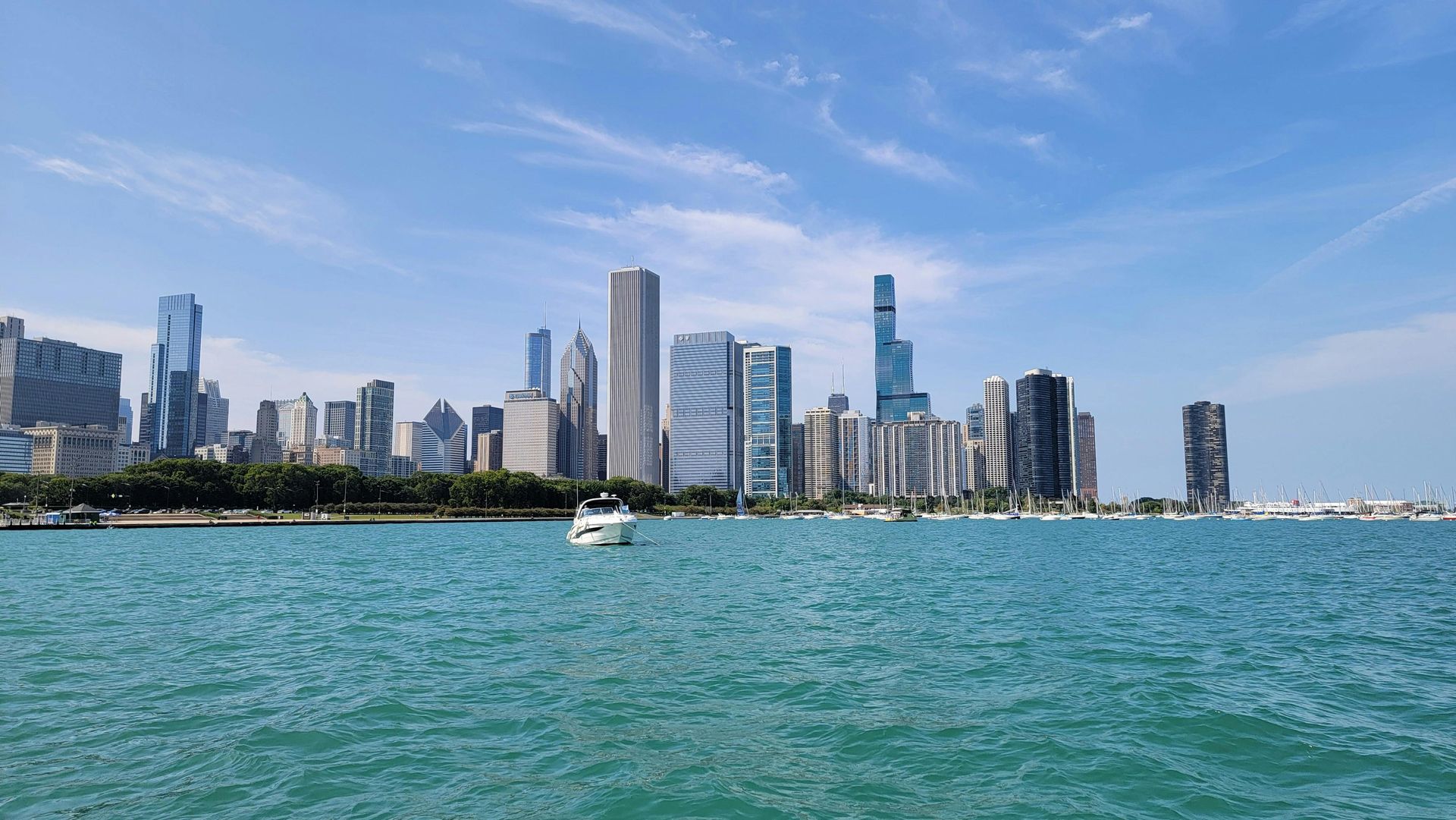 City skyline across turquoise water under a clear blue sky, with a small boat in the foreground