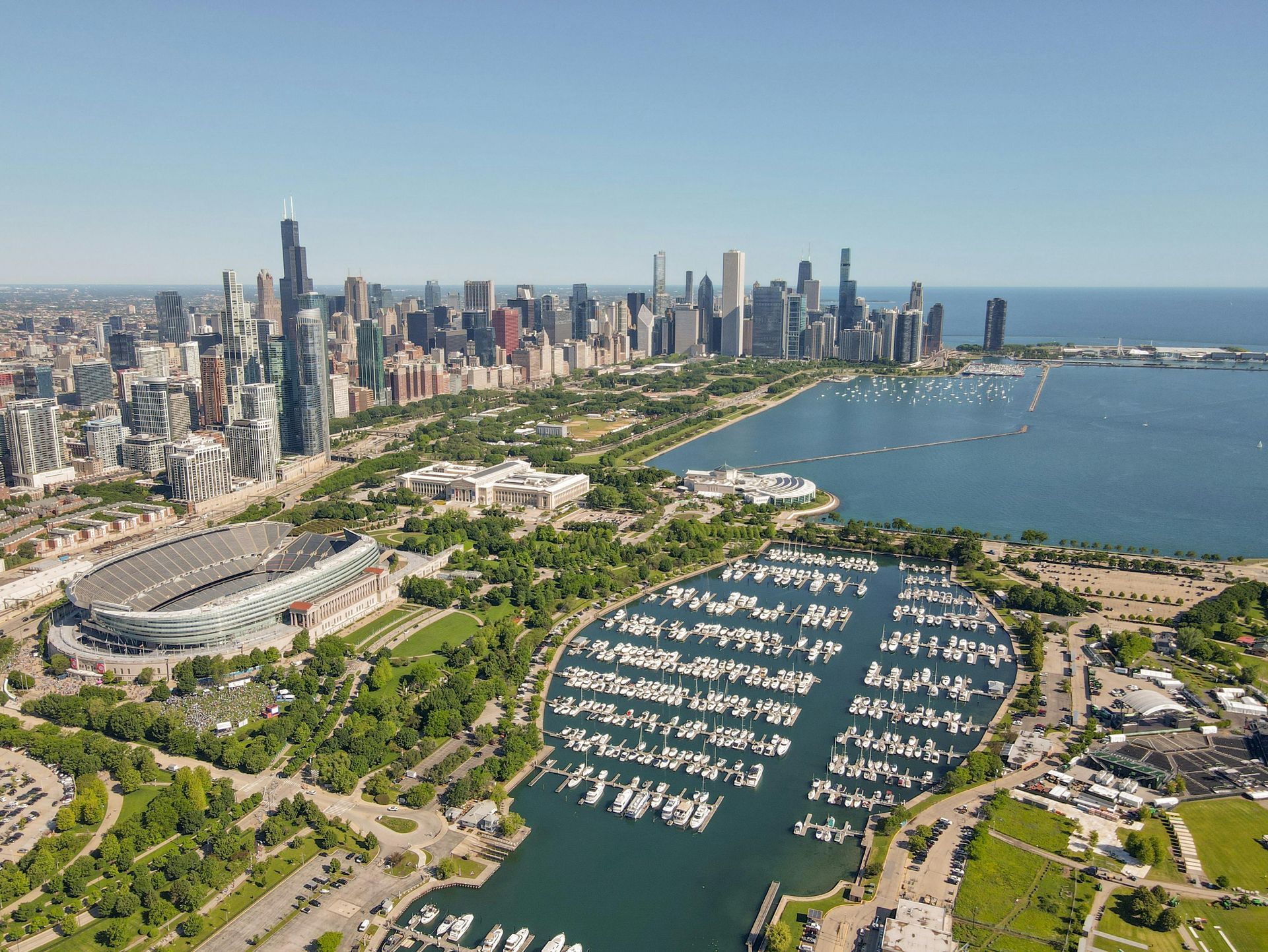 Aerial view of Chicago waterfront, with downtown skyline, a harbor full of boats, and a stadium nearby.