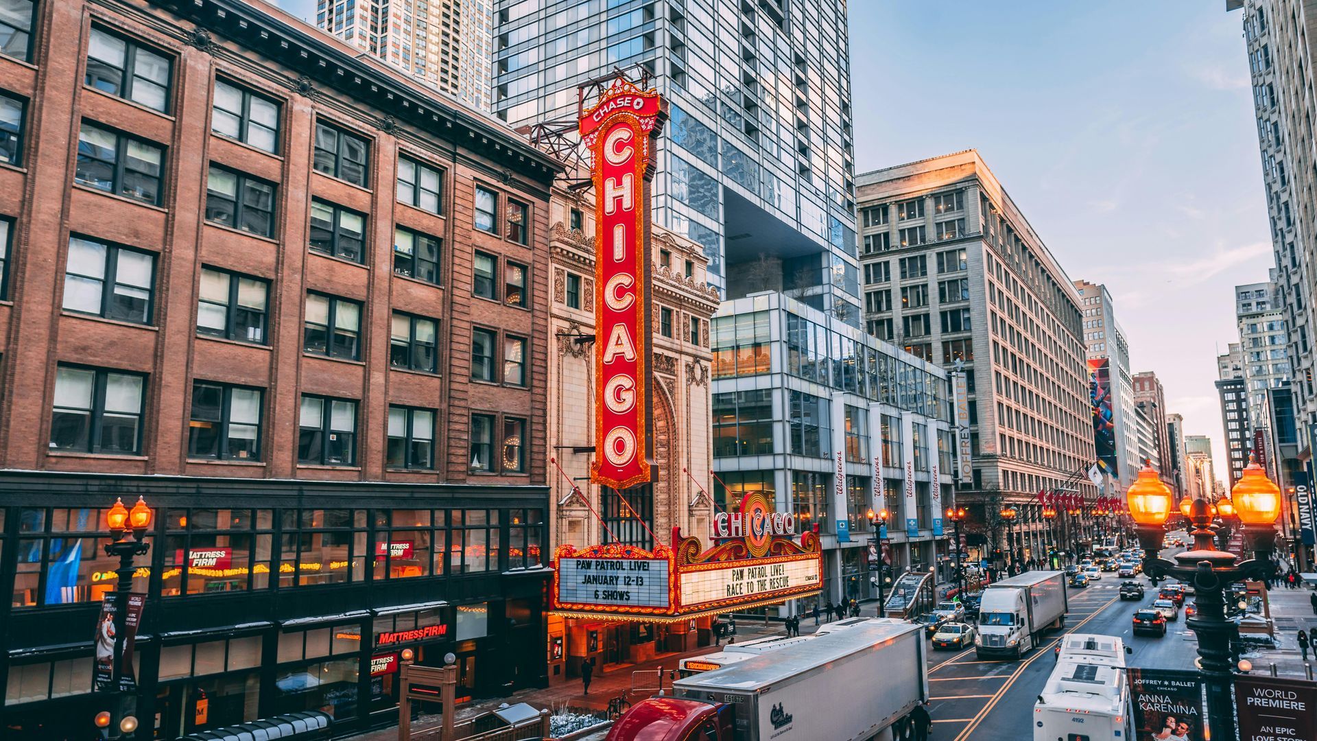 Chicago theater marquee on a busy city street with traffic and tall buildings at dusk