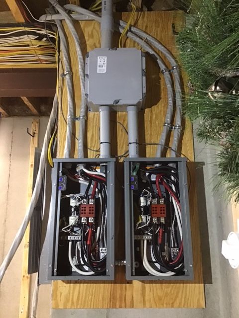 Electrical panel with conduit and wiring, mounted on wood.