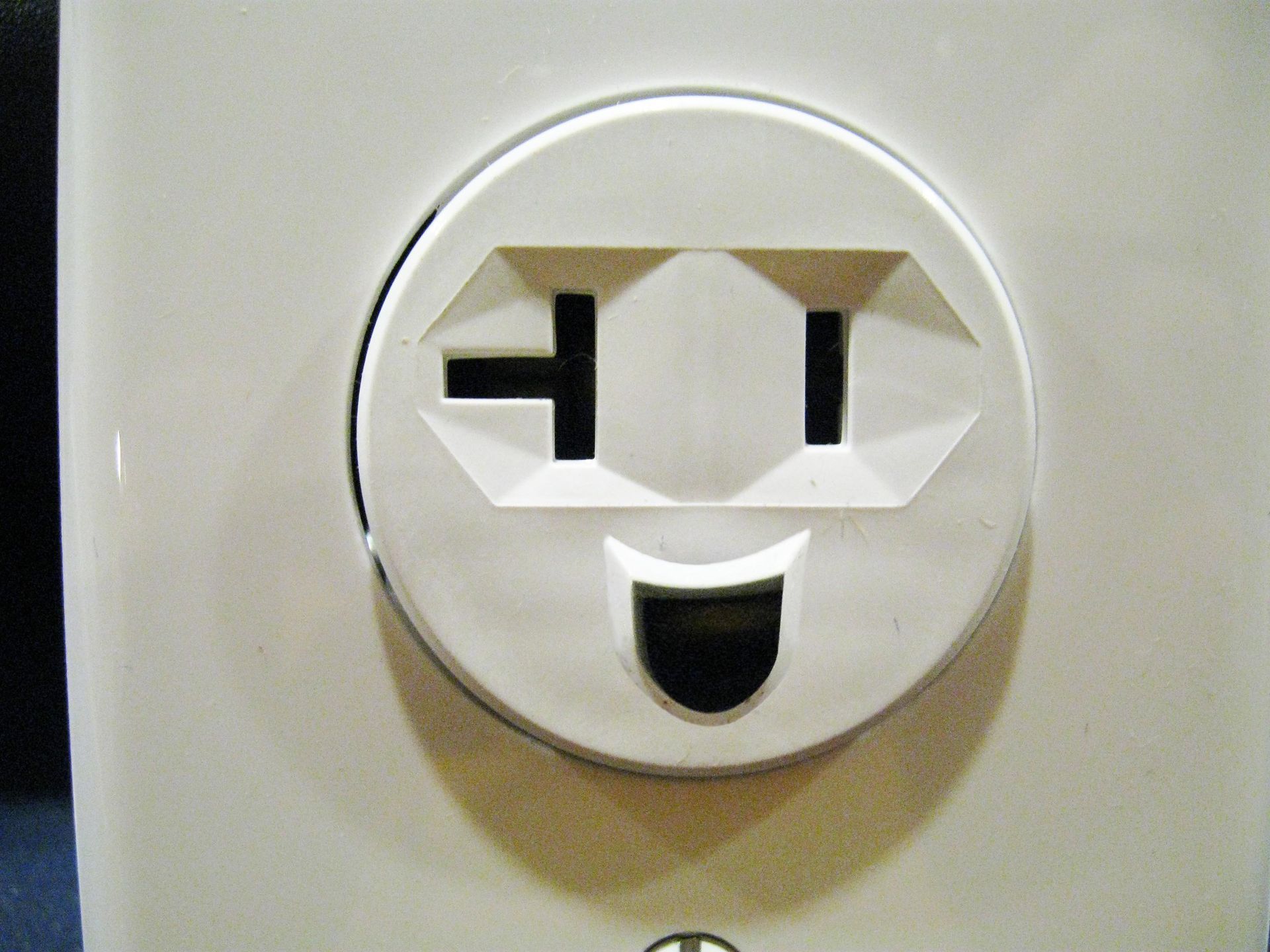 White electrical outlet with a face-like design, smiling.