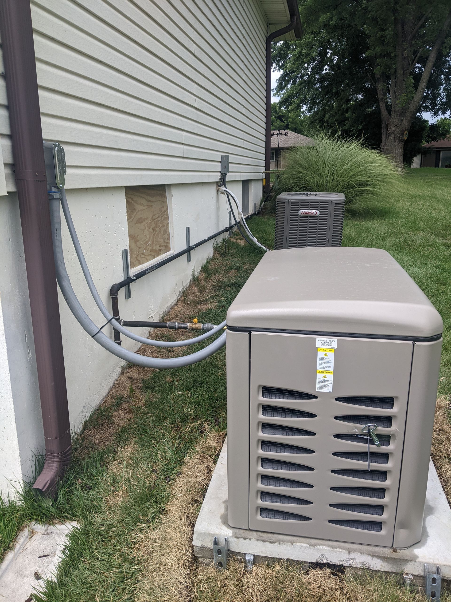 Air conditioner unit outside a house, with pipes and electrical wiring running along the wall.