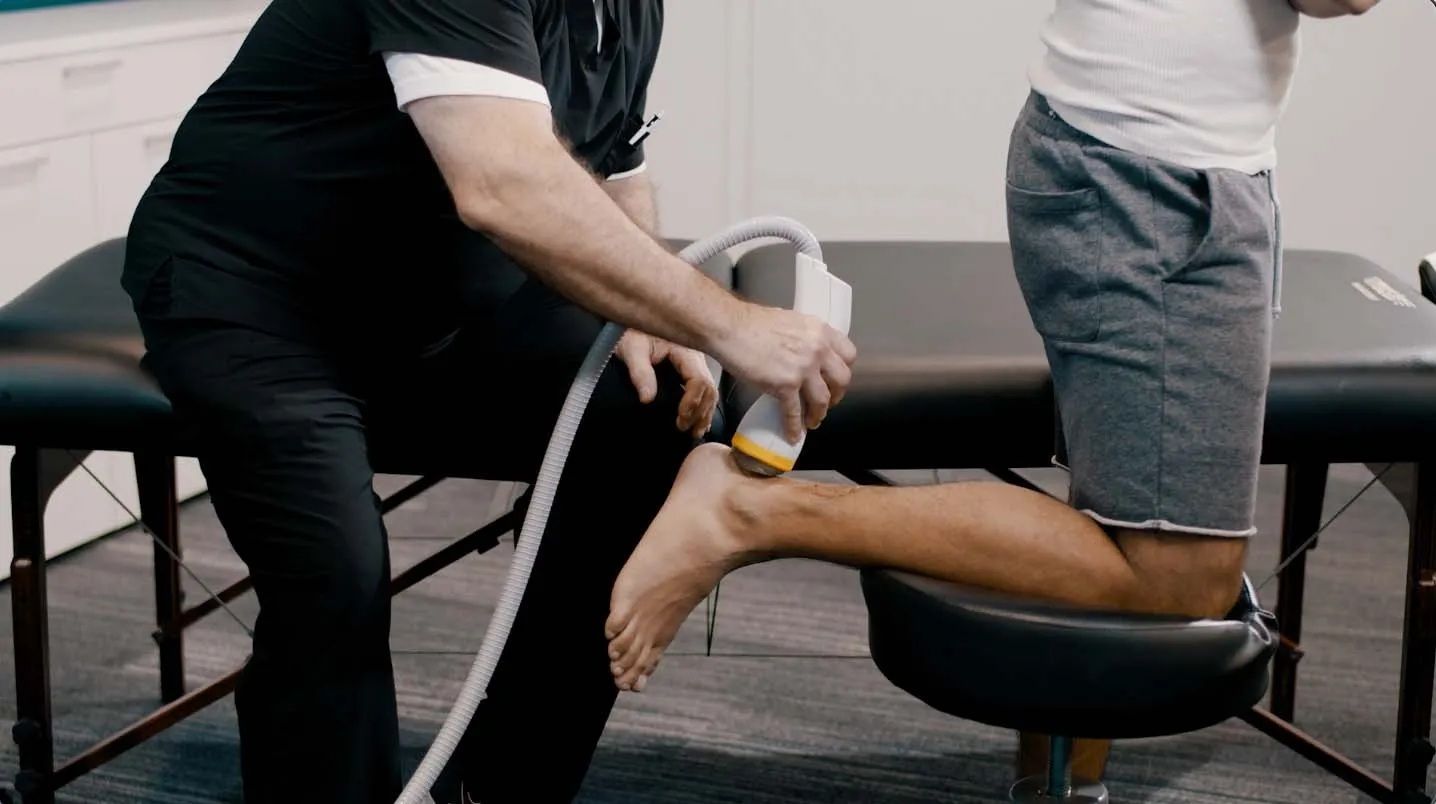 Doctor using a medical device on a person's ankle.