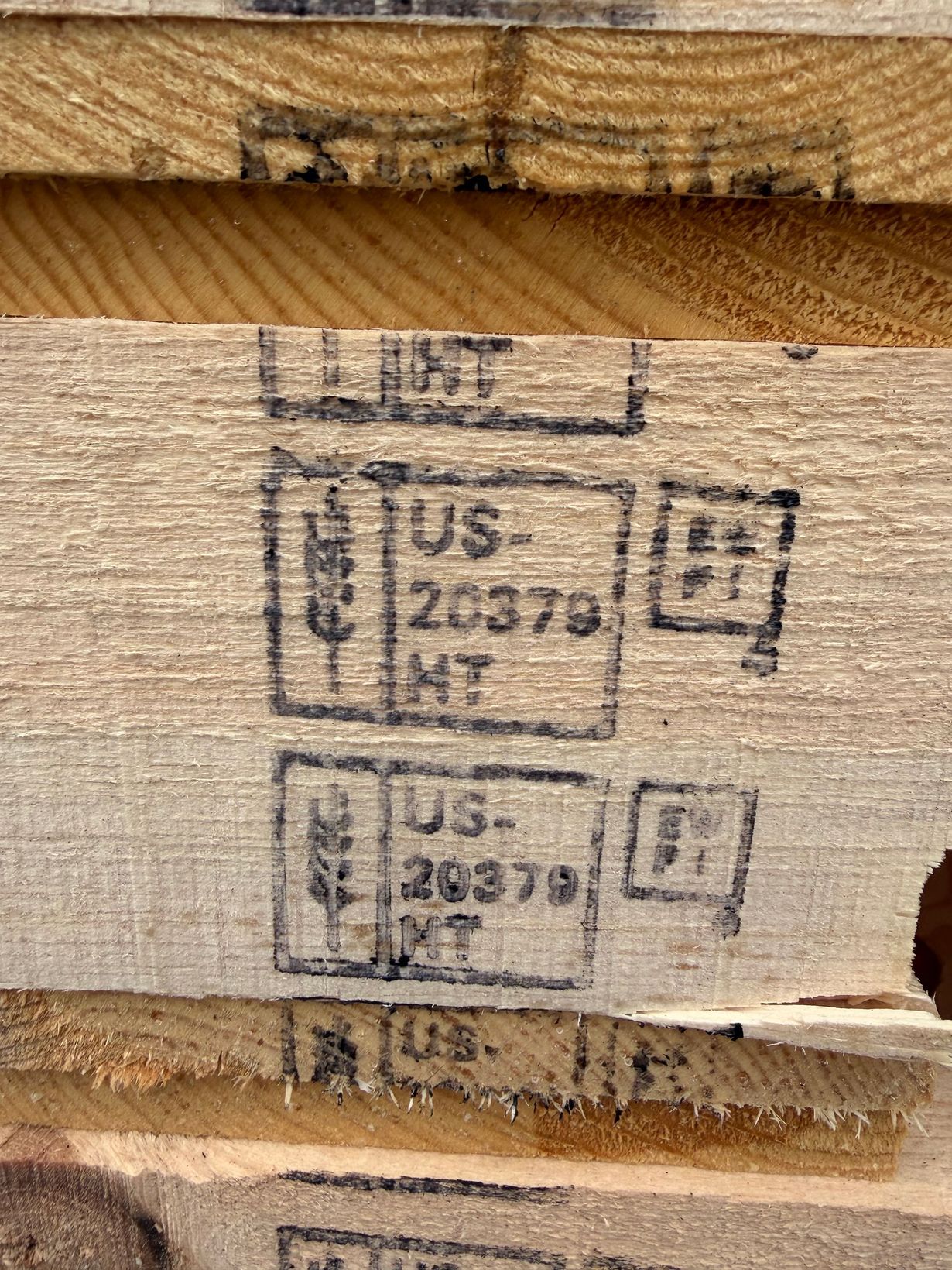 Close-up of heat-treated (HT) wood pallet stamps with the IPPC logo and US-20379 markings on light brown wooden slats.