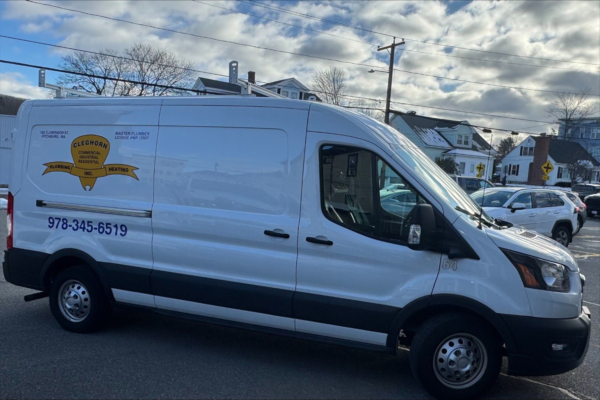 White cargo van parked outdoors with logo and phone number.