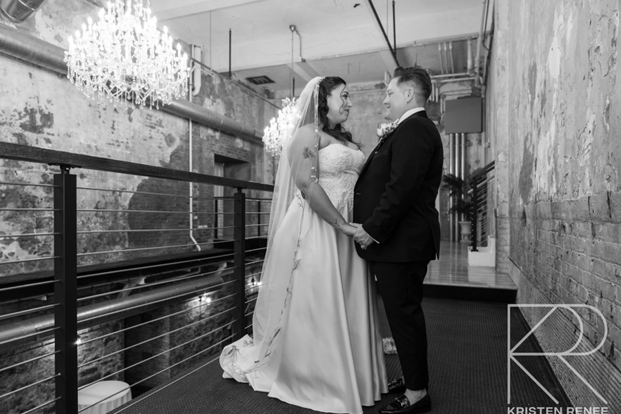 A bride and groom are holding hands in a black and white photo.