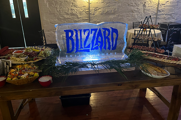 A large ice sculpture of the blizzard logo is sitting on top of a wooden table.