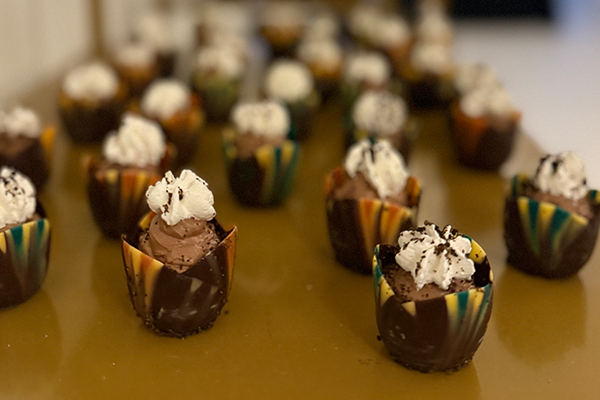 A bunch of chocolate cupcakes with whipped cream on top are sitting on a table.