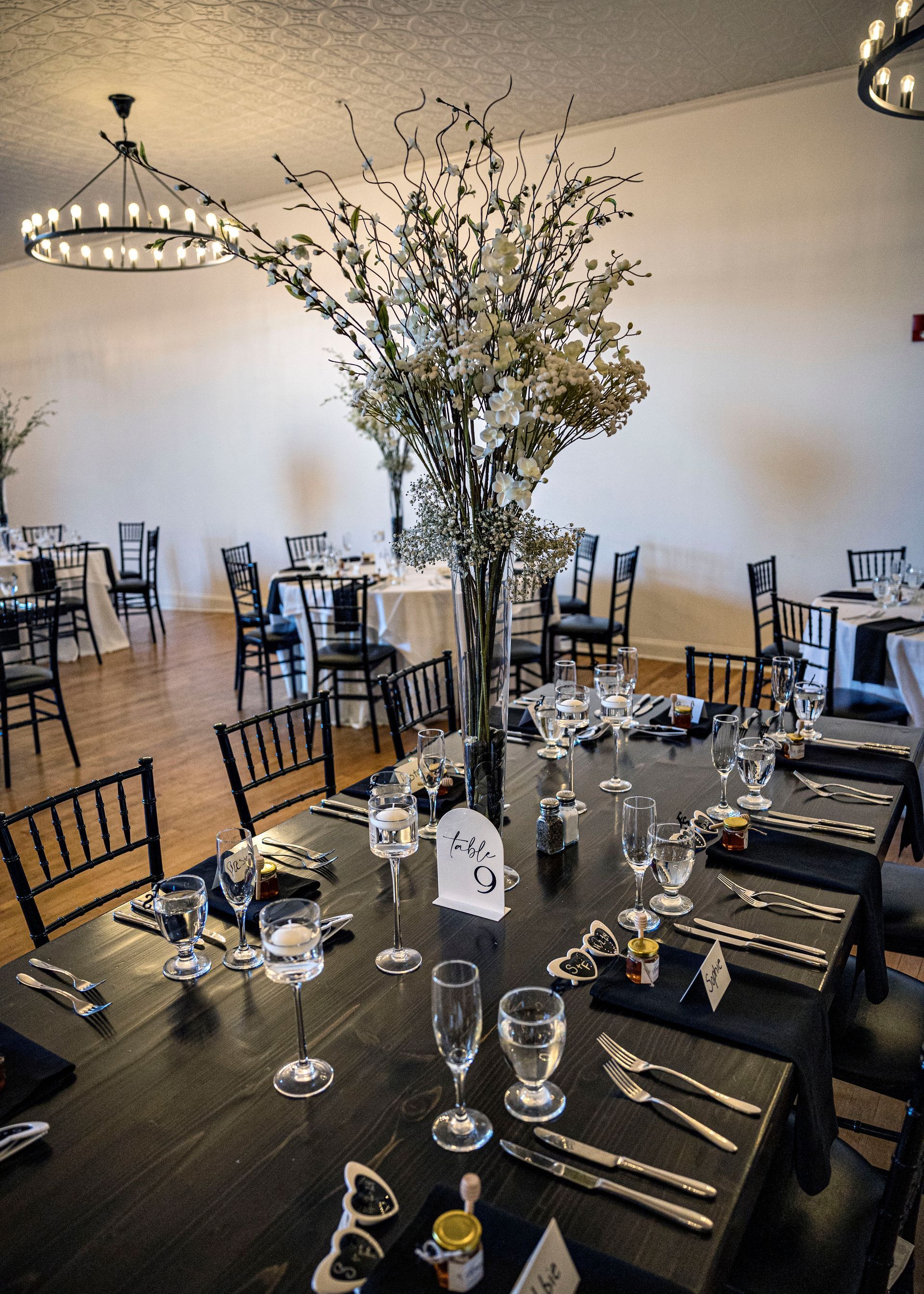 A table set for a wedding reception with a vase of flowers on it.
