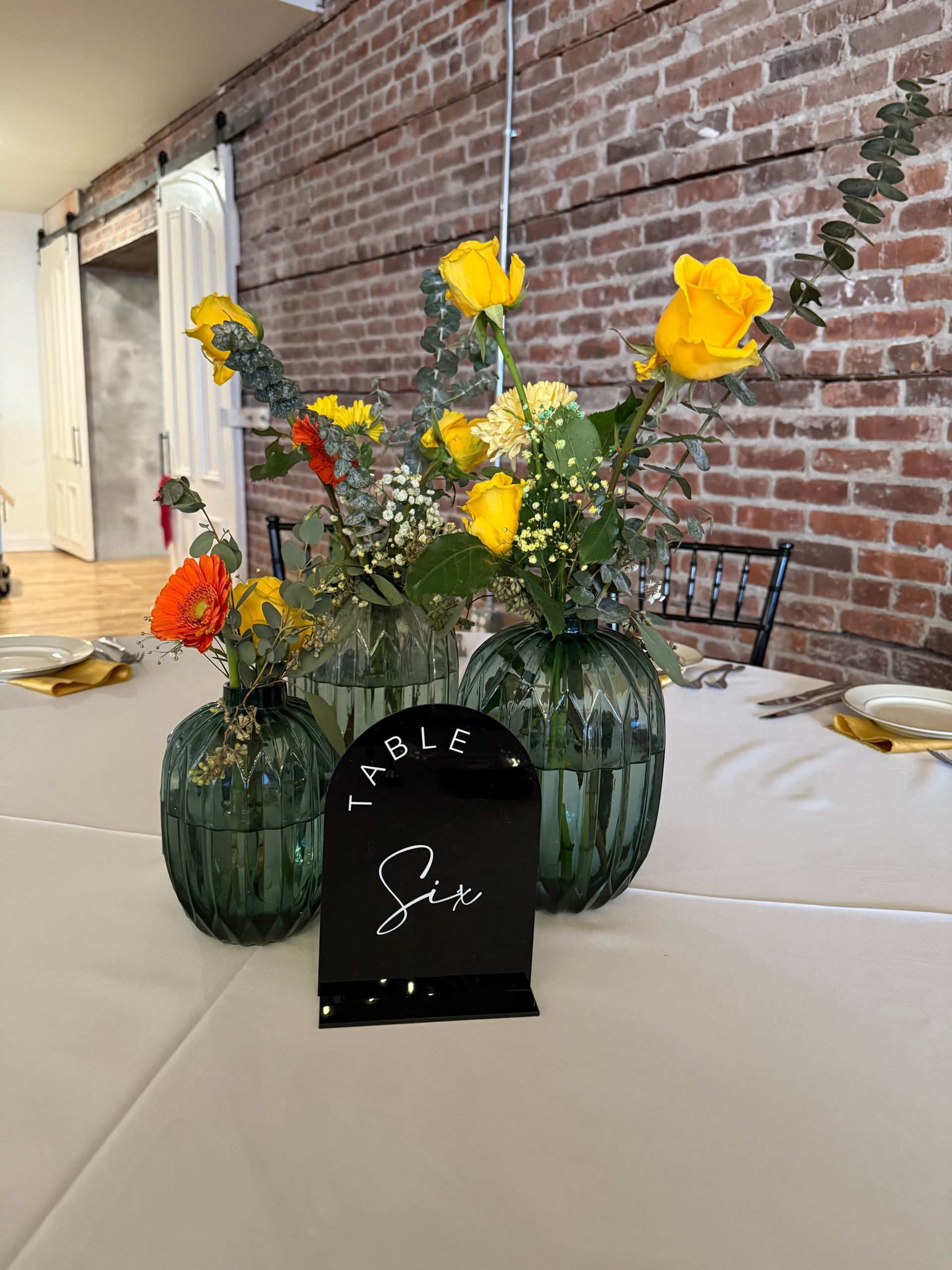 A table with a vase of flowers and a table number on it.