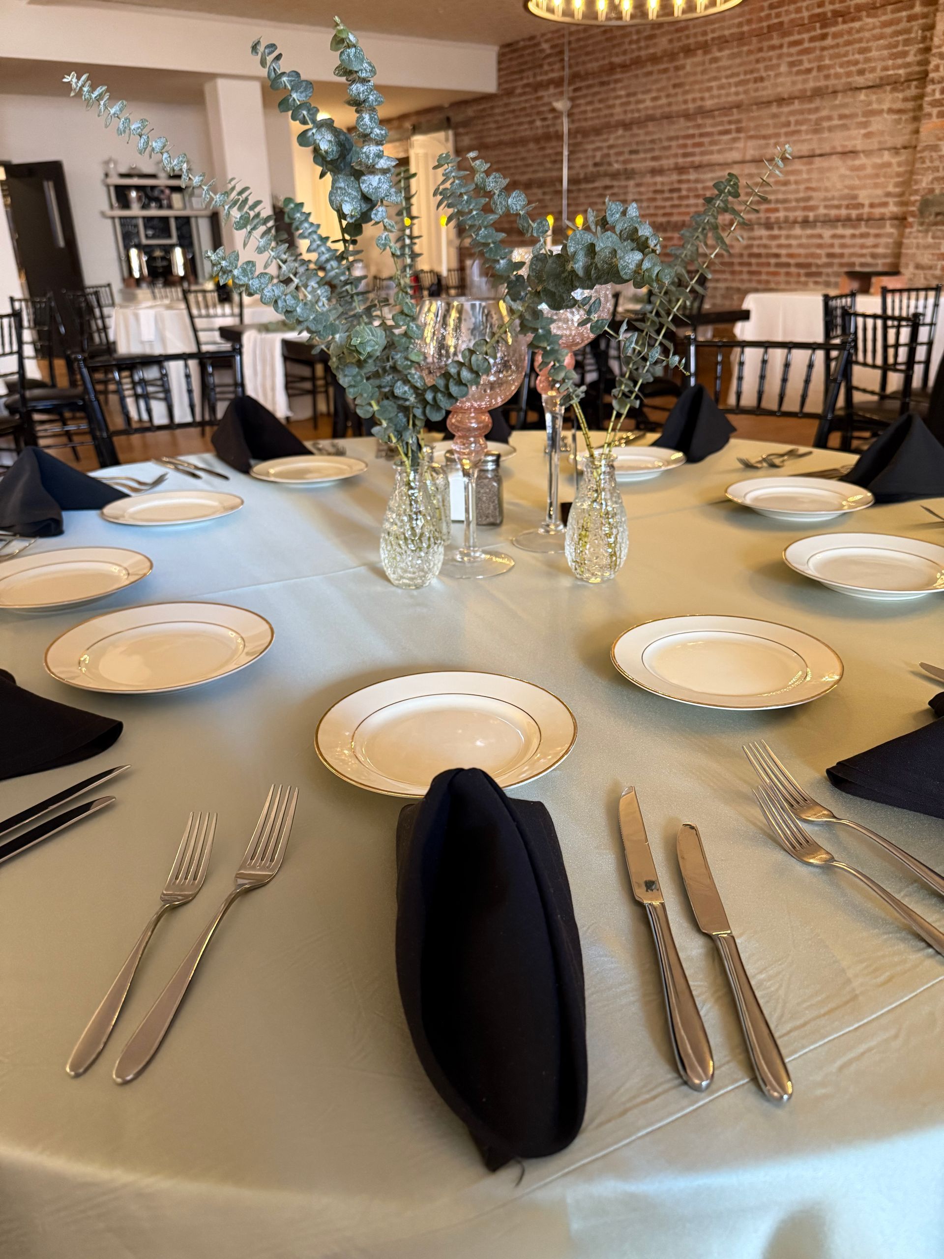 A table with plates , silverware , and a vase of flowers on it.