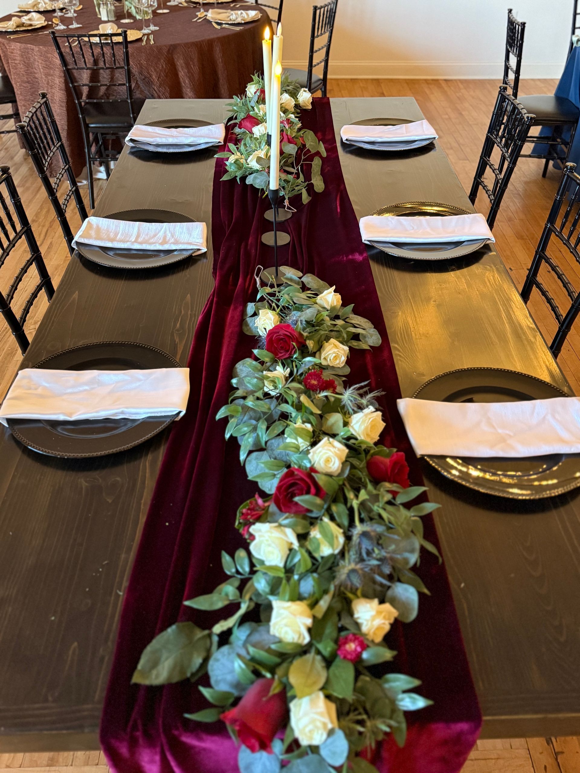 A long table with plates , napkins , candles and flowers on it.