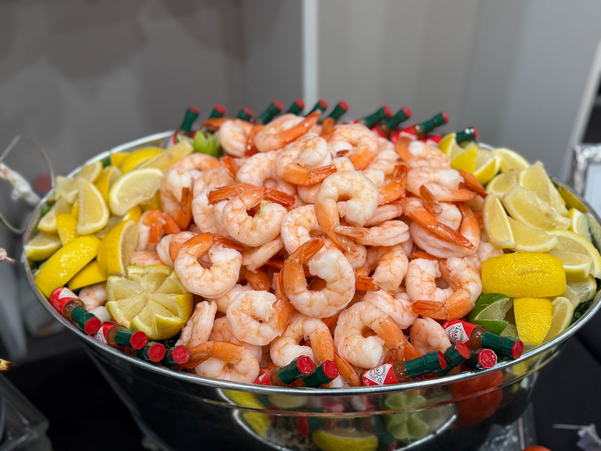 A bowl filled with shrimp , lemons , limes and tomatoes.