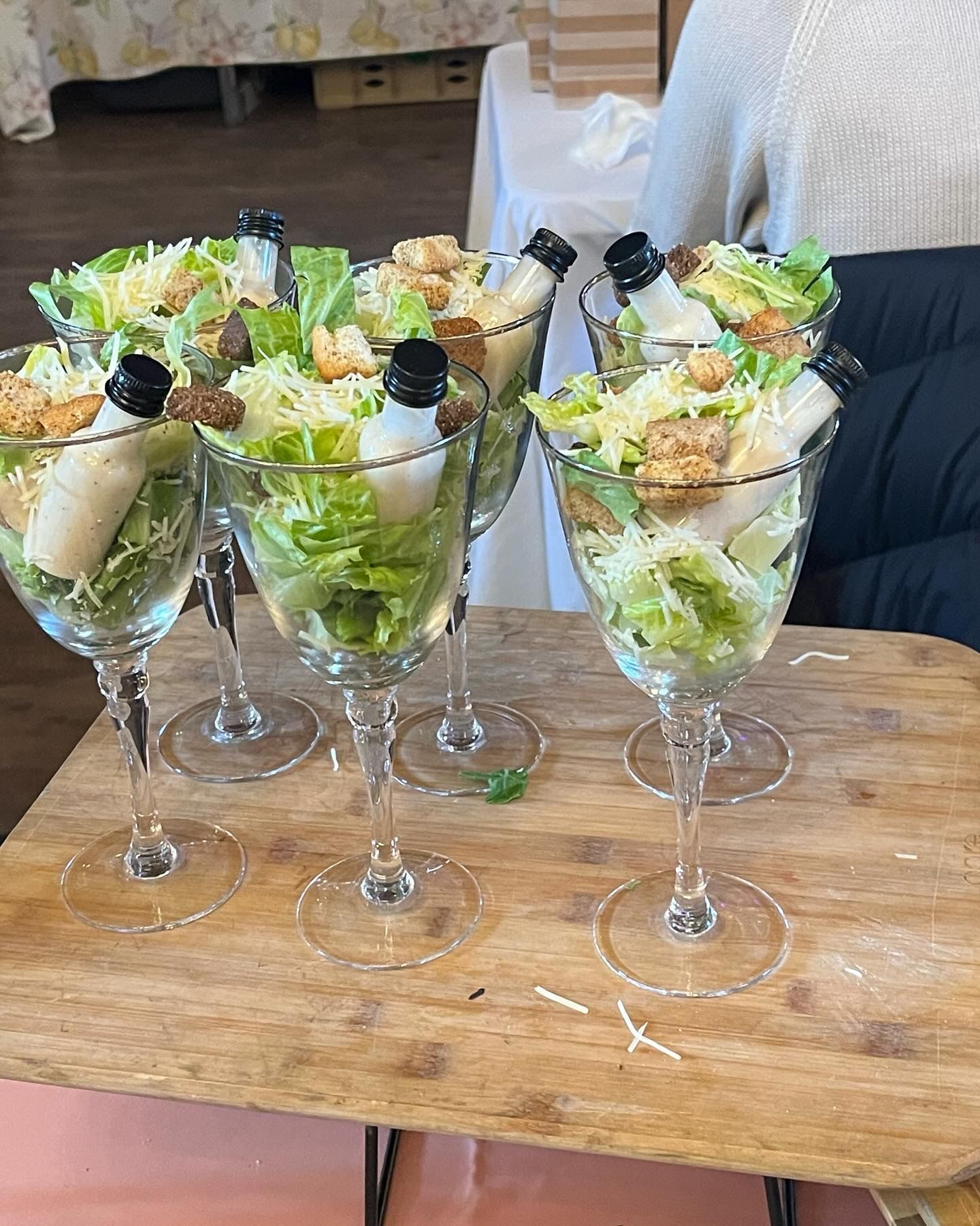 A table topped with wine glasses filled with salads.