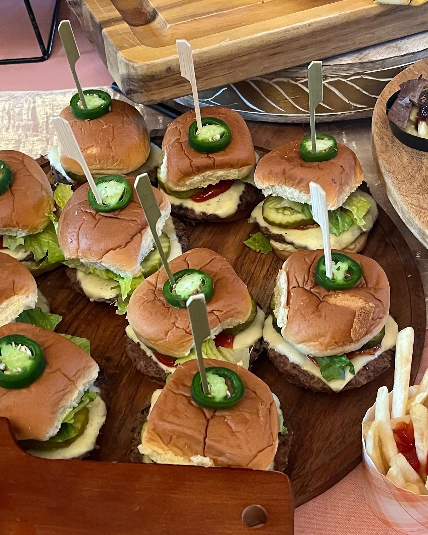 A wooden cutting board topped with hamburgers and french fries.