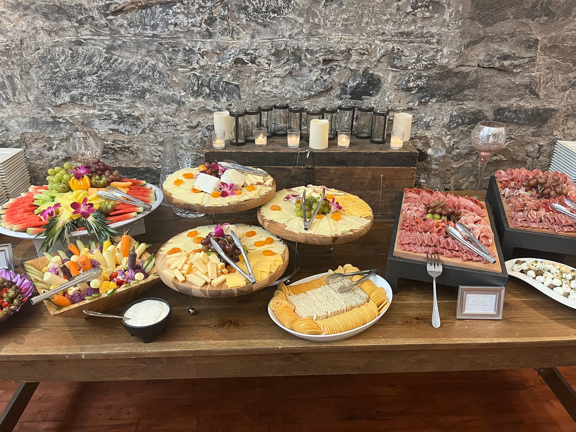 A wooden table topped with plates of food and candles.