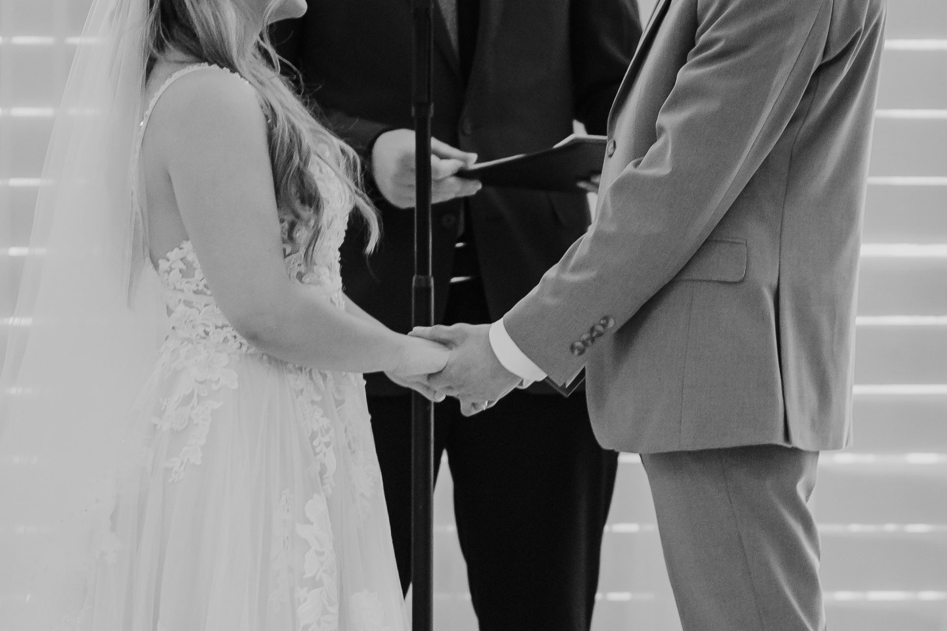 A black and white image of a bride and groom holding hands