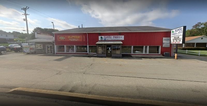 A red building with a lot of windows is sitting on the side of the road.