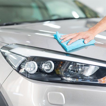 Man holds the microfiber in hand and polishes the car
