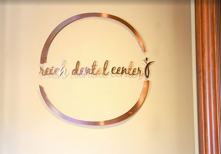 A sign for reich dental center is hanging on a wall.