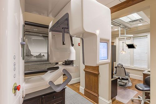 A dental office with a large x-ray machine and a dental chair.
