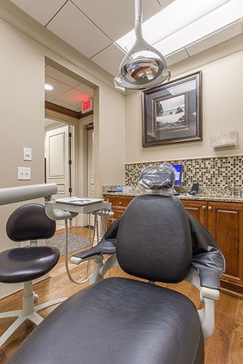 A dental chair in a dental office with a dental light hanging from the ceiling.